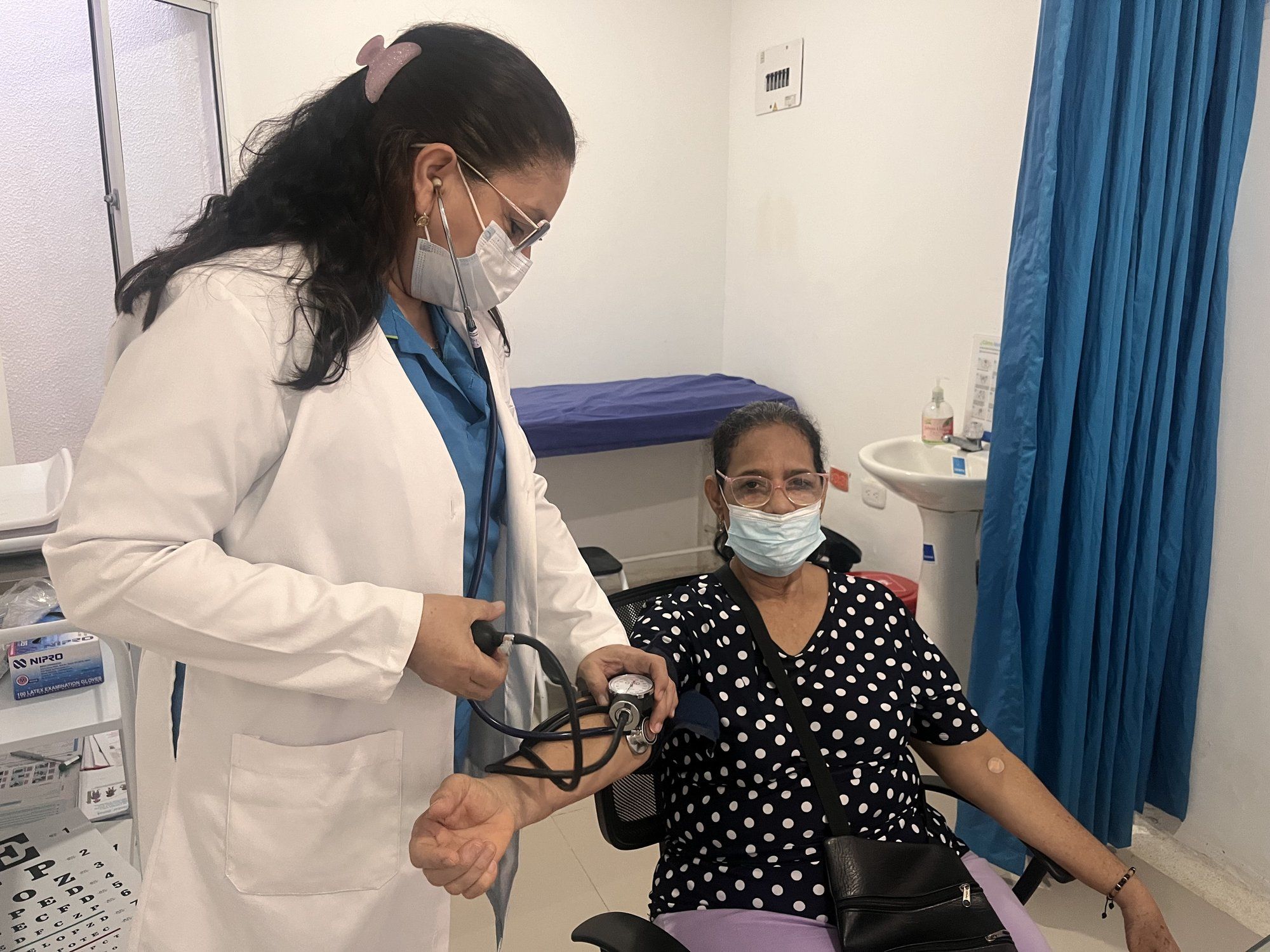 Médica tomando la tensión arterial a una usuaria en consulta