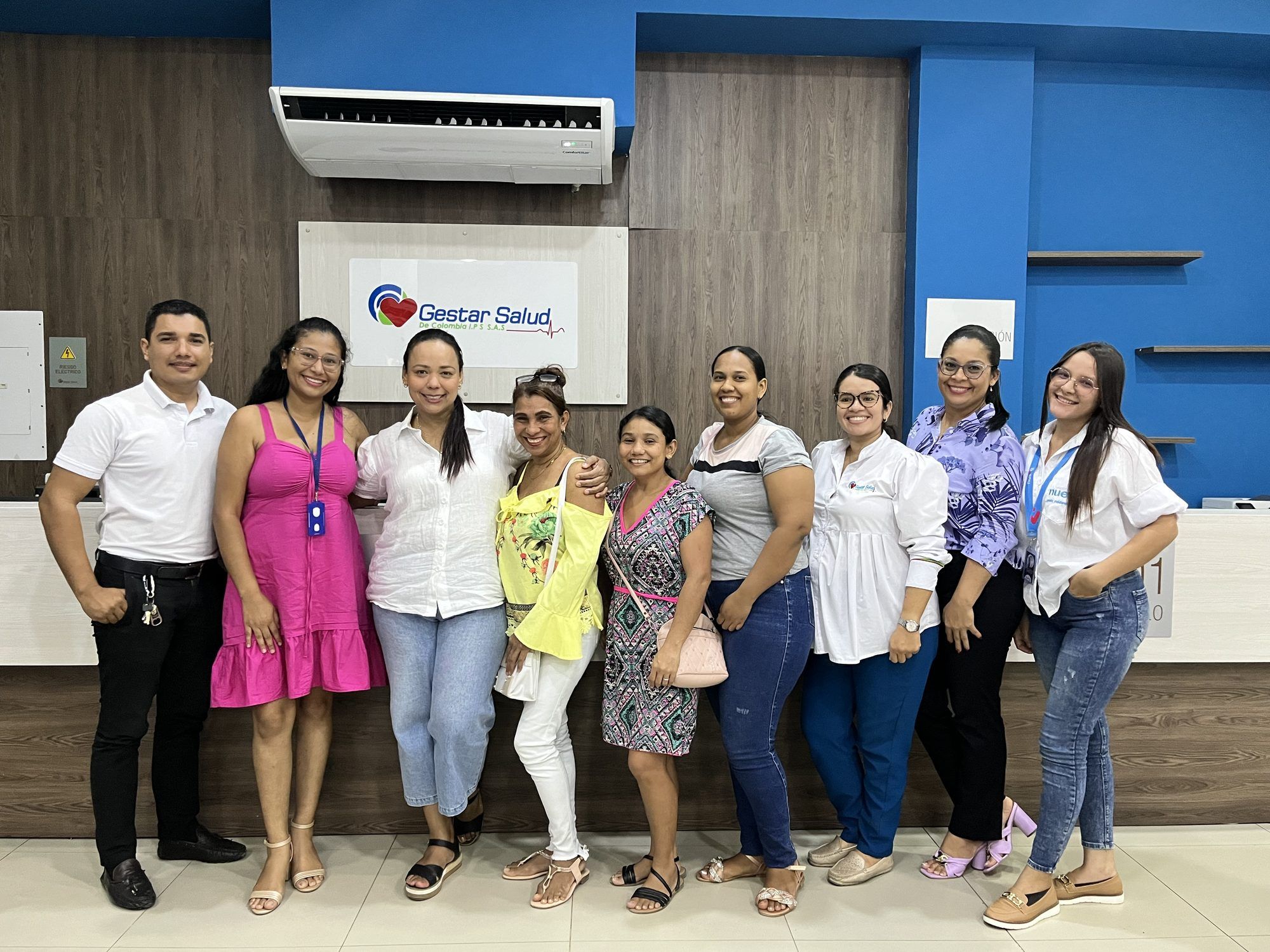 Equipo de una sede de Gestar Salud IPS frente al logo