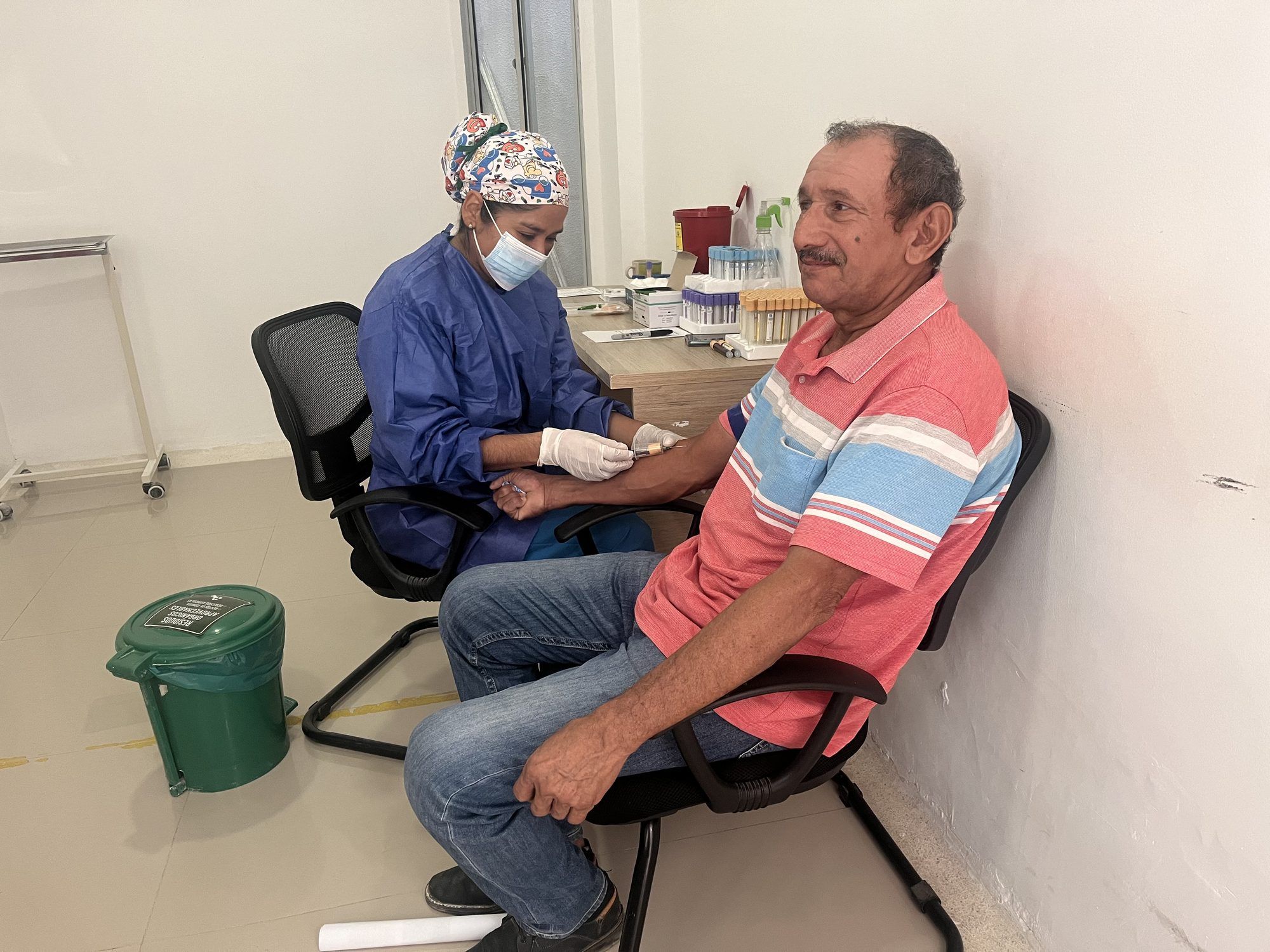 Toma de muestra de sangre a un usuario sonriente en el laboratorio